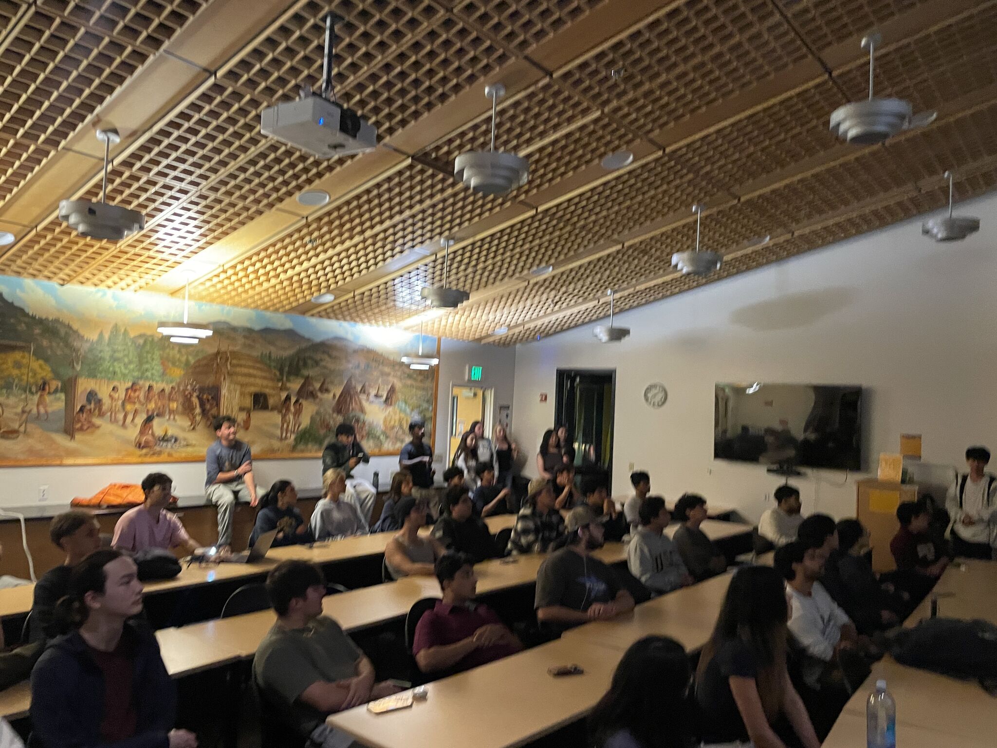 A full classroom of students seated at long tables at the first SFIG meeting of the year